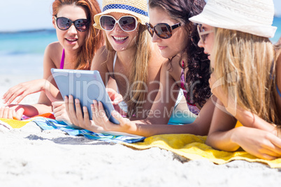 Happy friends wearing sun glasses and using tablet