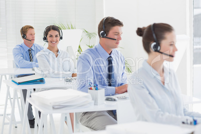 Business team working on computers and wearing headsets