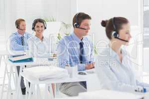 Business team working on computers and wearing headsets