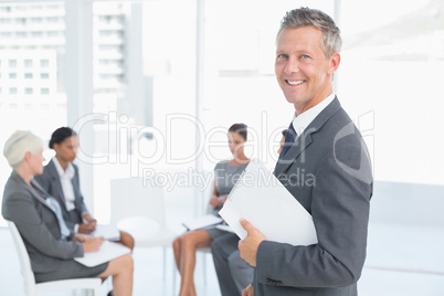 Businessman writing notes with colleagues behind