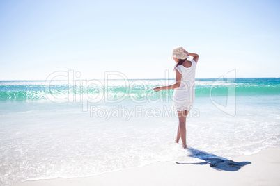 Pretty brunette wearing straw hat and walking in the water