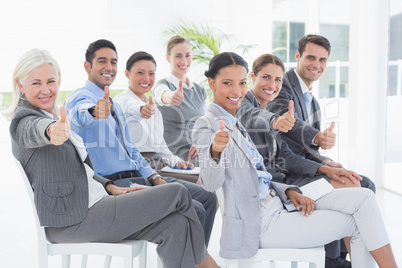 Business people looking at camera with thumbs up