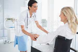 Happy doctor smiling at her patient in wheelchair