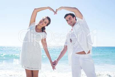 Happy couple forming heart shape with their hands