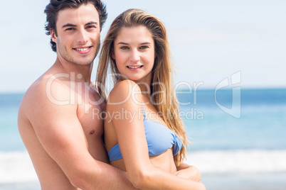 Happy couple in swimsuit looking at camera and embracing