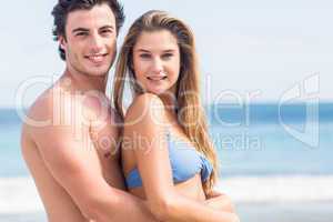 Happy couple in swimsuit looking at camera and embracing