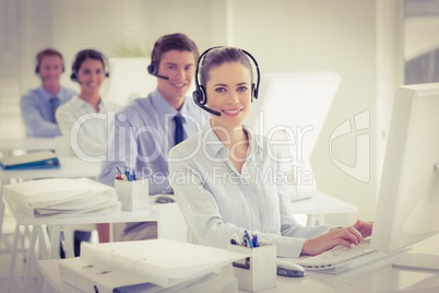 Business team working on computers and wearing headsets