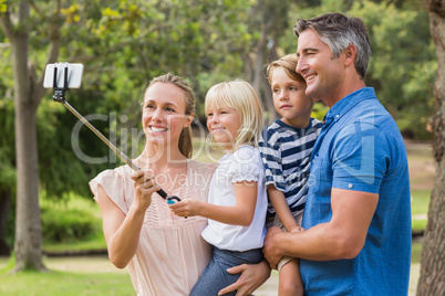 Happy family using a selfie stick in the park