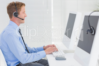 Handsome agent with headset typing on keyboard