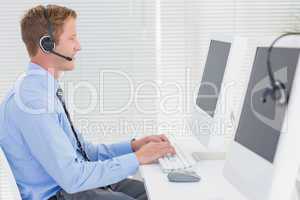 Handsome agent with headset typing on keyboard