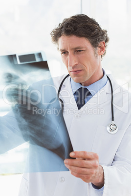 Serious doctor looking at X-ray