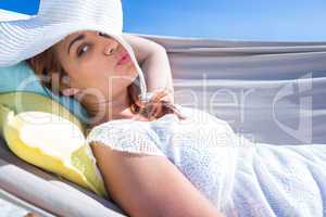 Pretty brunette posing with straw hat in the hammock