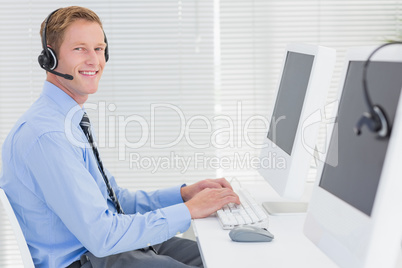 Handsome agent with headset typing on keyboard