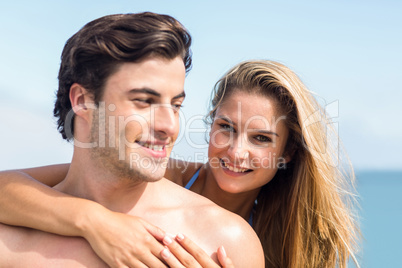 Happy couple in swimsuit looking at camera and embracing