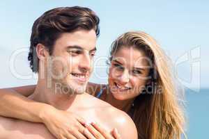 Happy couple in swimsuit looking at camera and embracing