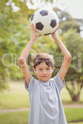 Boy looking at camera and holding a soccer ball in the park