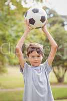 Boy looking at camera and holding a soccer ball in the park