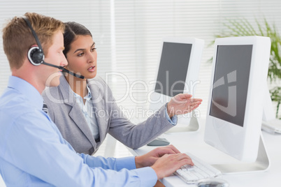 Business team working on computers and wearing headsets