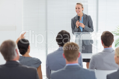 Pretty businesswoman talking in microphone during conference