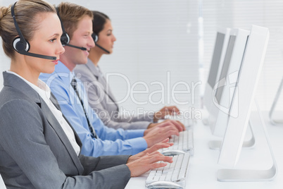 Business team working on computers and wearing headsets