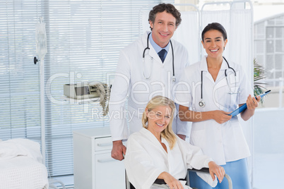 Doctors and patient in wheelchair smiling at camera