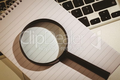 Magnifying glass and notepad on laptop