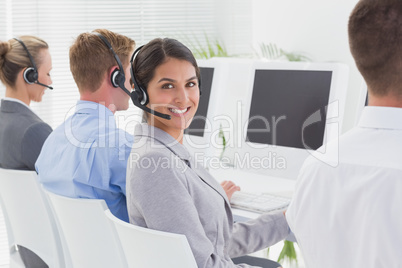 Business team working on computers and wearing headsets