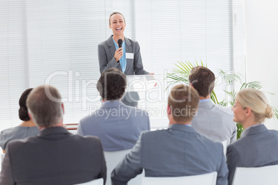 Pretty businesswoman talking in microphone during conference