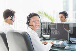 Businesswoman looking at camera while her colleagues working