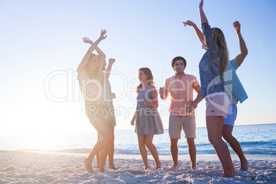 Happy friends dancing on the sand