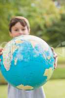 Smiling boy holding an earth globe in the park