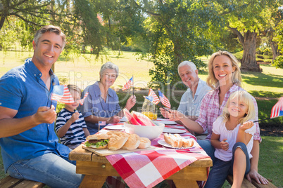 Happy family having picnic and holding american flag