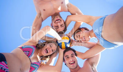 Group of friends standing in circle and holding ball