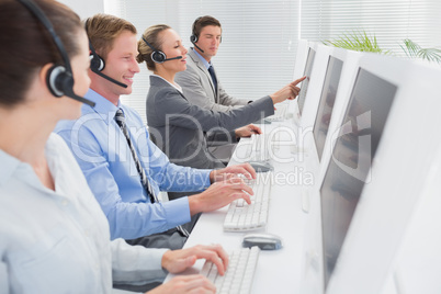 Business team working on computers and wearing headsets