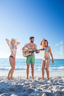 Handsome man playing guitar and his friends dancing