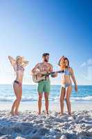 Handsome man playing guitar and his friends dancing