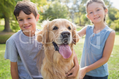 Smiling sibling with their dog in the park