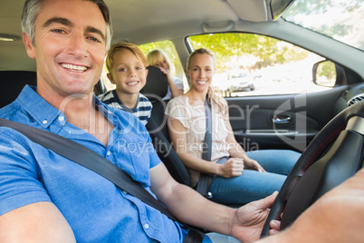 Happy family smiling at the camera in the car