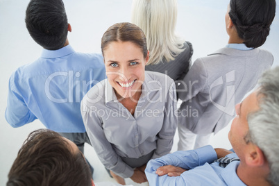 Businesswoman looking at camera with her colleague around her