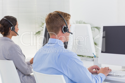 Business team working on computers and wearing headsets