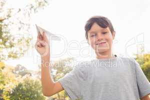 Smiling boy with paper plane in the park
