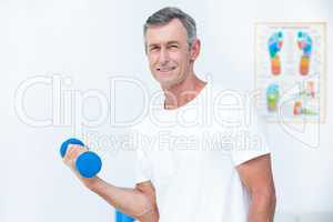 Patient looking at camera and lifting dumbbell