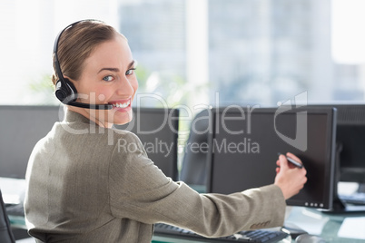 Smiling businesswoman touching computer screen with pen