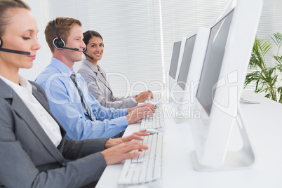Business team working on computers and wearing headsets