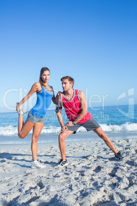 Happy couple stretching together beside the water