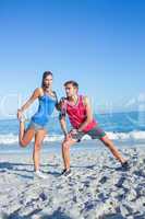 Happy couple stretching together beside the water