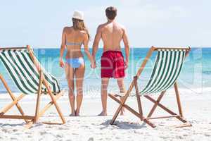 Happy couple holding hands and looking at the sea