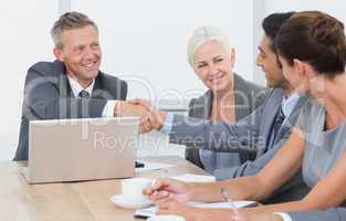 Executives shaking hands in board room meeting