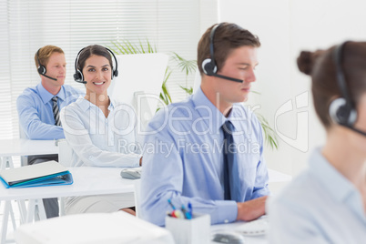 Business team working on computers and wearing headsets