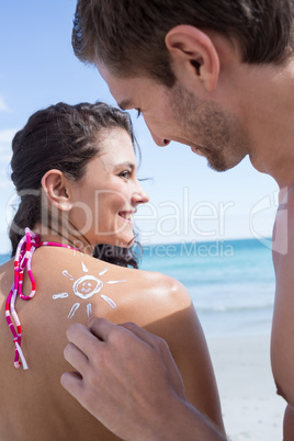 Handsome man putting sun tan lotion on his girlfriend